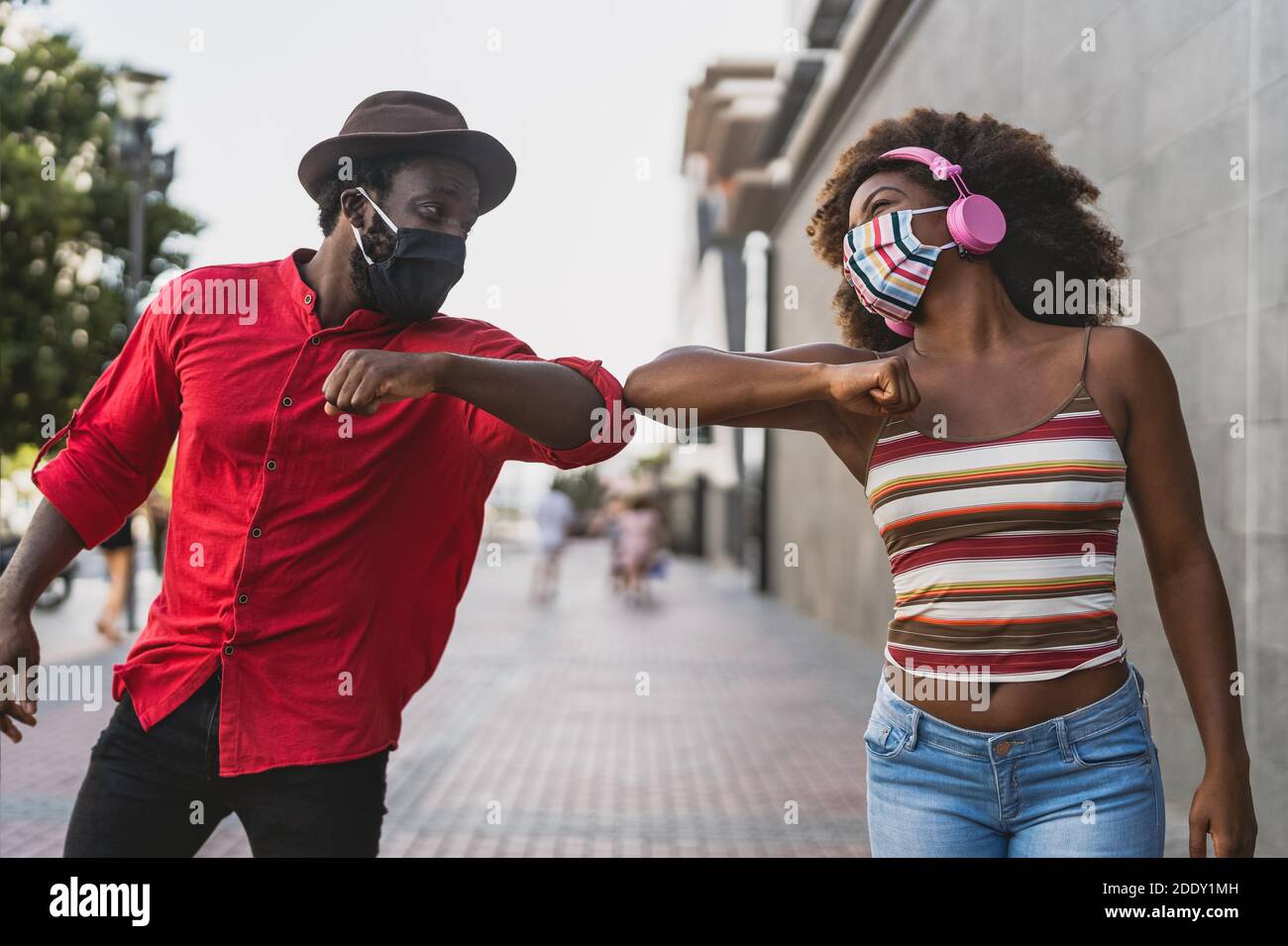 African friends wearing face protective mask while doing new social distance greetings bumping elbows Stock Photo