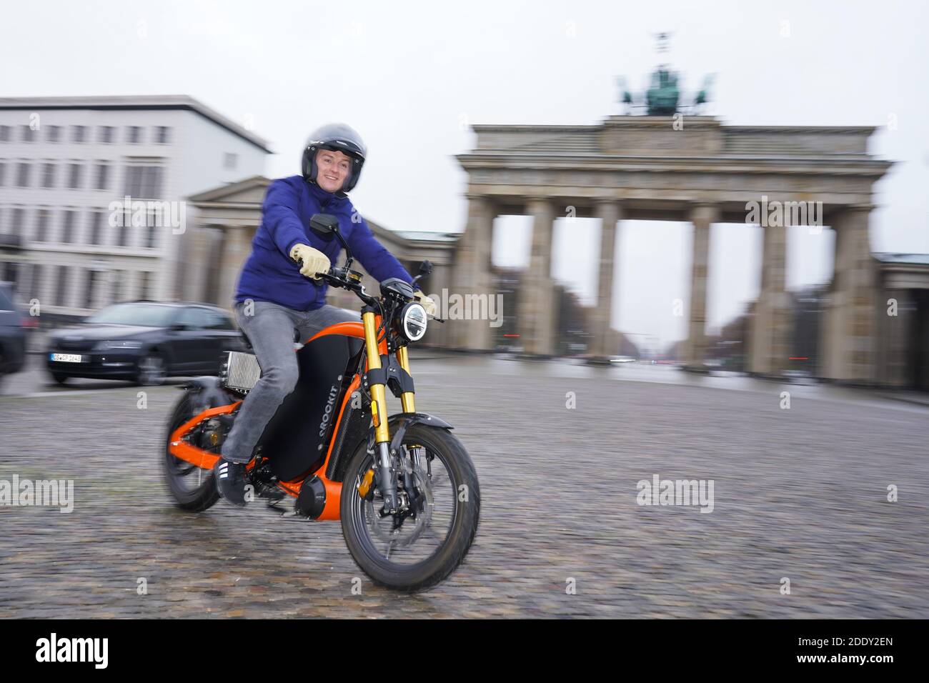 27 November 2020, Berlin: Aaron Troschke, moderator, influencer and start-up entrepreneur, rides an eROCKIT in front of the Brandenburg Gate. The content marketing professional has invested in the Brandenburg vehicle manufacturer eROCKIT Systems. In the pedal-controlled electric motorcycle, the electronics register the muscle power used by the rider and multiply it many times over. With a slight pedalling movement, you can reach up to 89 km/h. Photo: Jörg Carstensen/dpa Stock Photo