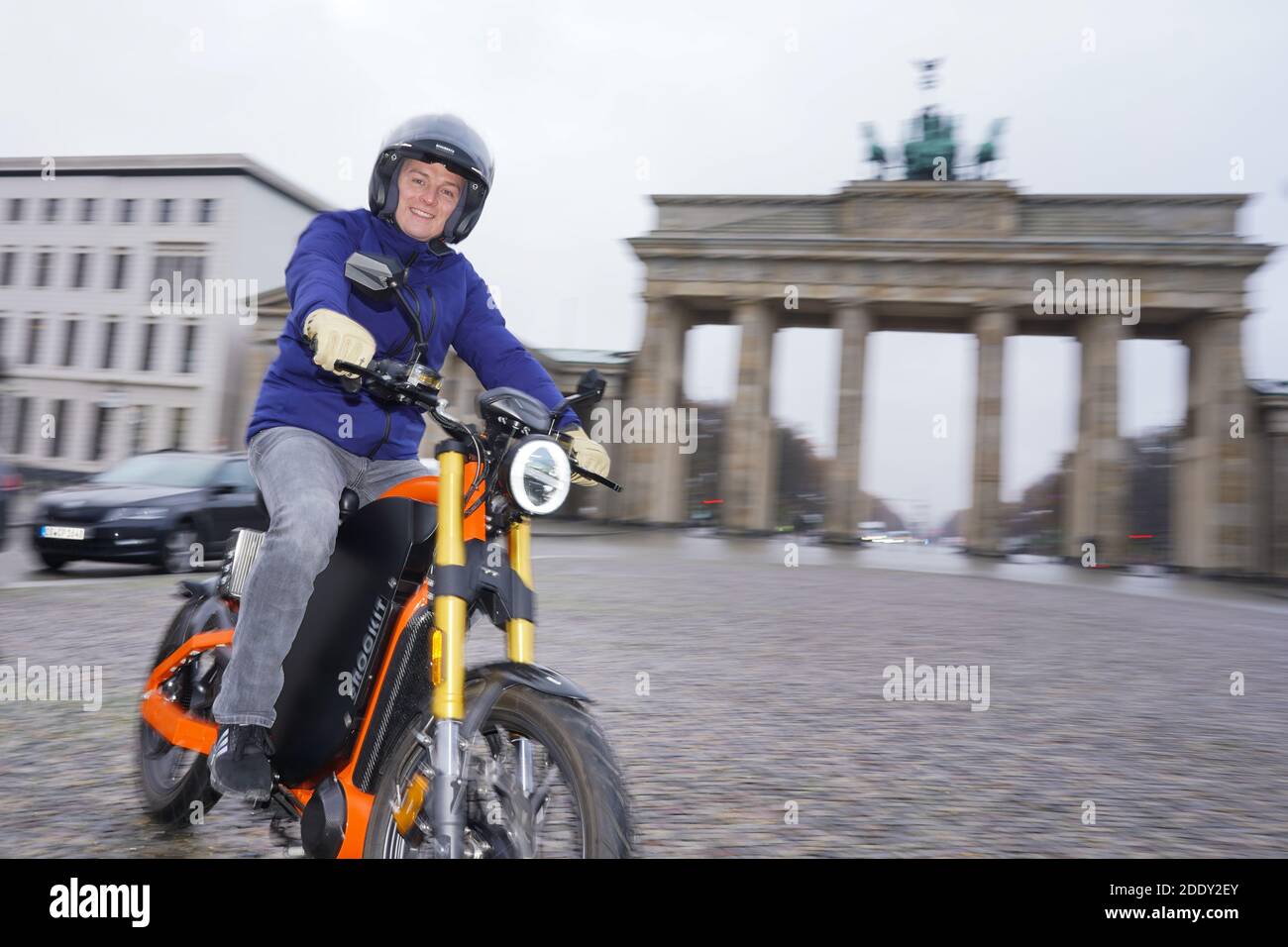 27 November 2020, Berlin: Aaron Troschke, moderator, influencer and start-up entrepreneur, rides an eROCKIT in front of the Brandenburg Gate. The content marketing professional has invested in the Brandenburg vehicle manufacturer eROCKIT Systems. In the pedal-controlled electric motorcycle, the electronics register the muscle power used by the rider and multiply it many times over. With a slight pedalling movement, you can reach up to 89 km/h. Photo: Jörg Carstensen/dpa Stock Photo