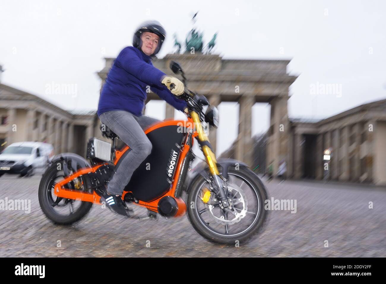 27 November 2020, Berlin: Aaron Troschke, moderator, influencer and start-up entrepreneur, rides an eROCKIT in front of the Brandenburg Gate. The content marketing professional has invested in the Brandenburg vehicle manufacturer eROCKIT Systems. In the pedal-controlled electric motorcycle, the electronics register the muscle power used by the rider and multiply it many times over. With a slight pedalling movement, you can reach up to 89 km/h. Photo: Jörg Carstensen/dpa Stock Photo