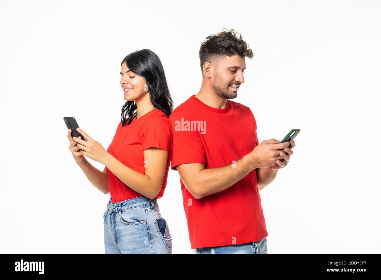 Couple standing back to back and using smartphone Stock Photo