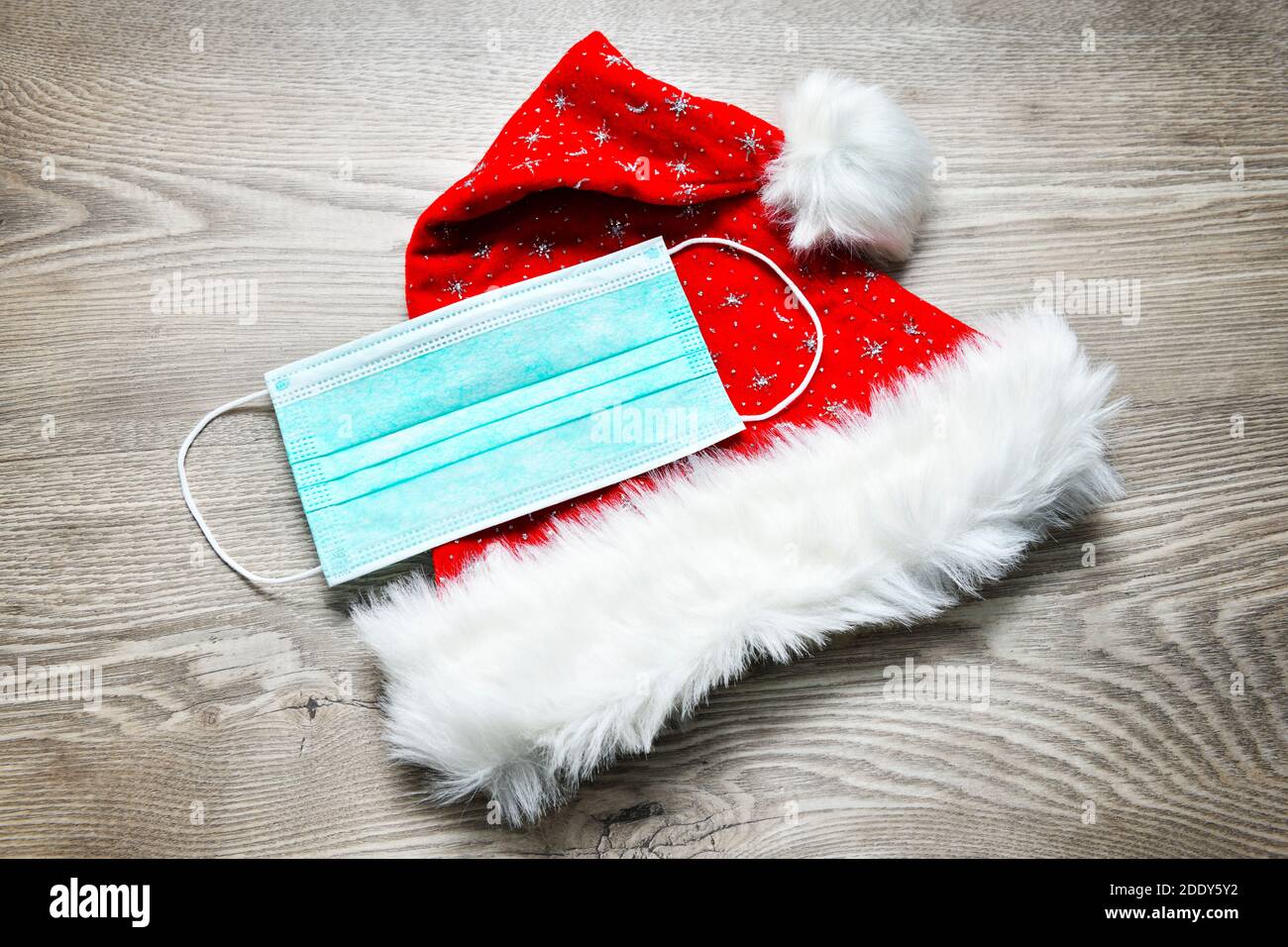Face mask lying on Santa's hat, Corona Christmas Stock Photo