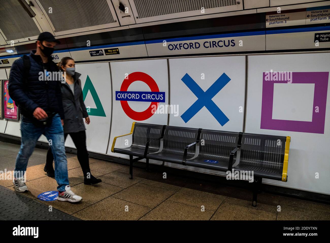 London, UK. 27 Nov 2020. In time for the arrival of the PS5 console signage at Oxford Circus has been updated with the console's trademark square, circle, triangle and cross. Inside the tube station the four symbols appear alongside the station name and roundel. By chance (or not) the Oxford Circus Microsoft store (maker of its main competitor the X-box) sits right outside one of these exits. People are still out in central london, despite the new lockdown which is now in force. Credit: Guy Bell/Alamy Live News Stock Photo