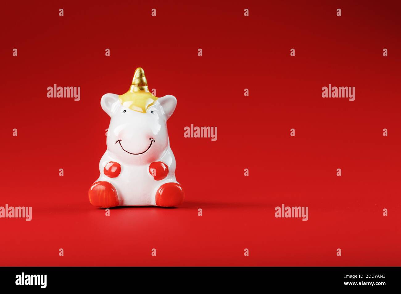 Unicorn figurine on a red background with free space. Symbol of good