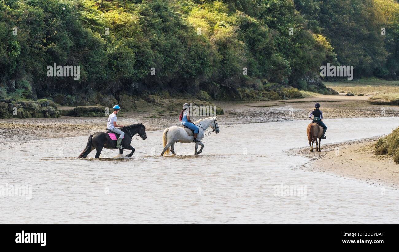 A panoramic image of horse riders crossing the tidal Gannel River at