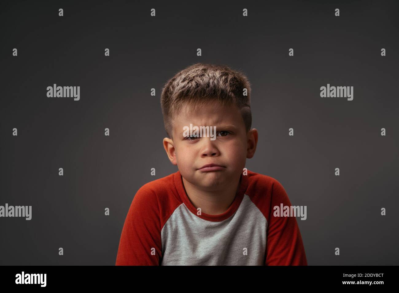 Little boy showing with his face I Dont Like It to his parents isolated on grey background. Fake child emotions. Facial expressions, emotions Stock Photo