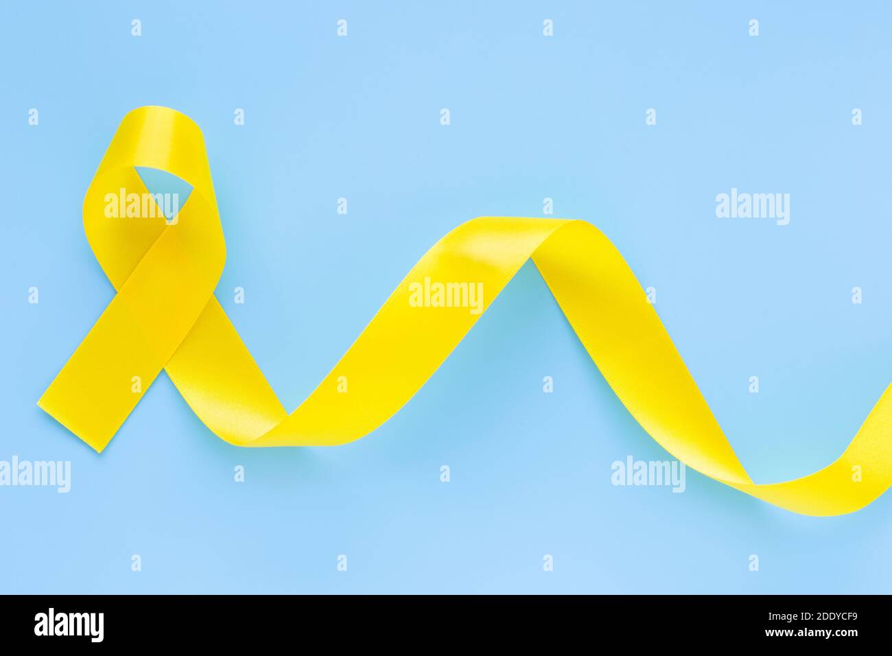 Yellow ribbon on light blue background, copy space. Bone cancer, Sarcoma Awareness, childhood cancer awareness, cholangiocarcinoma, gallbladder cancer Stock Photo