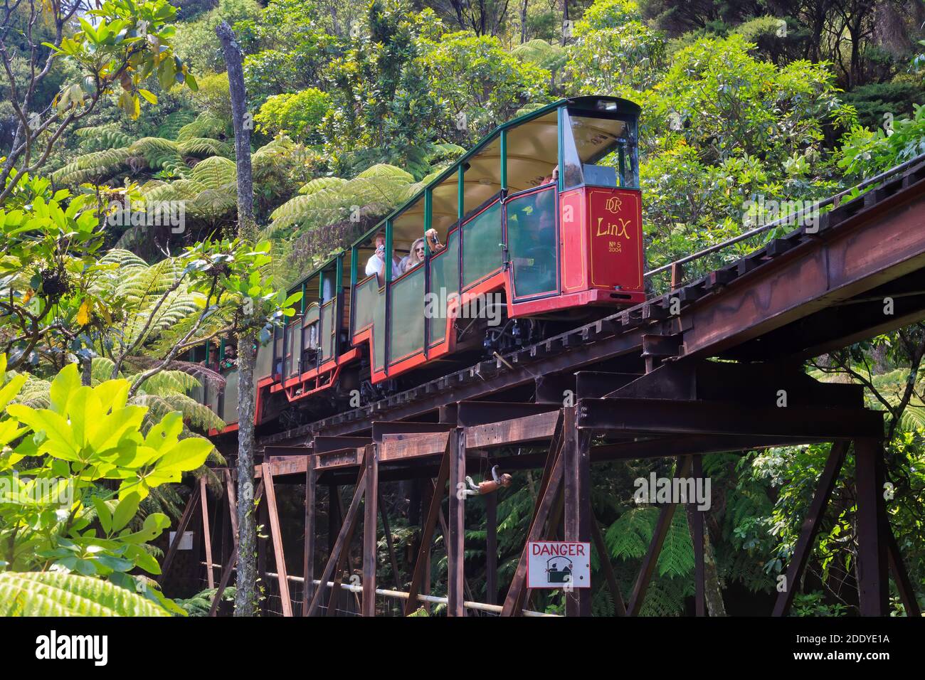 Driving Creek Railway, a tourist attraction on the Coromandel Peninsula, New Zealand. A colorful rail car crosses a bridge Stock Photo