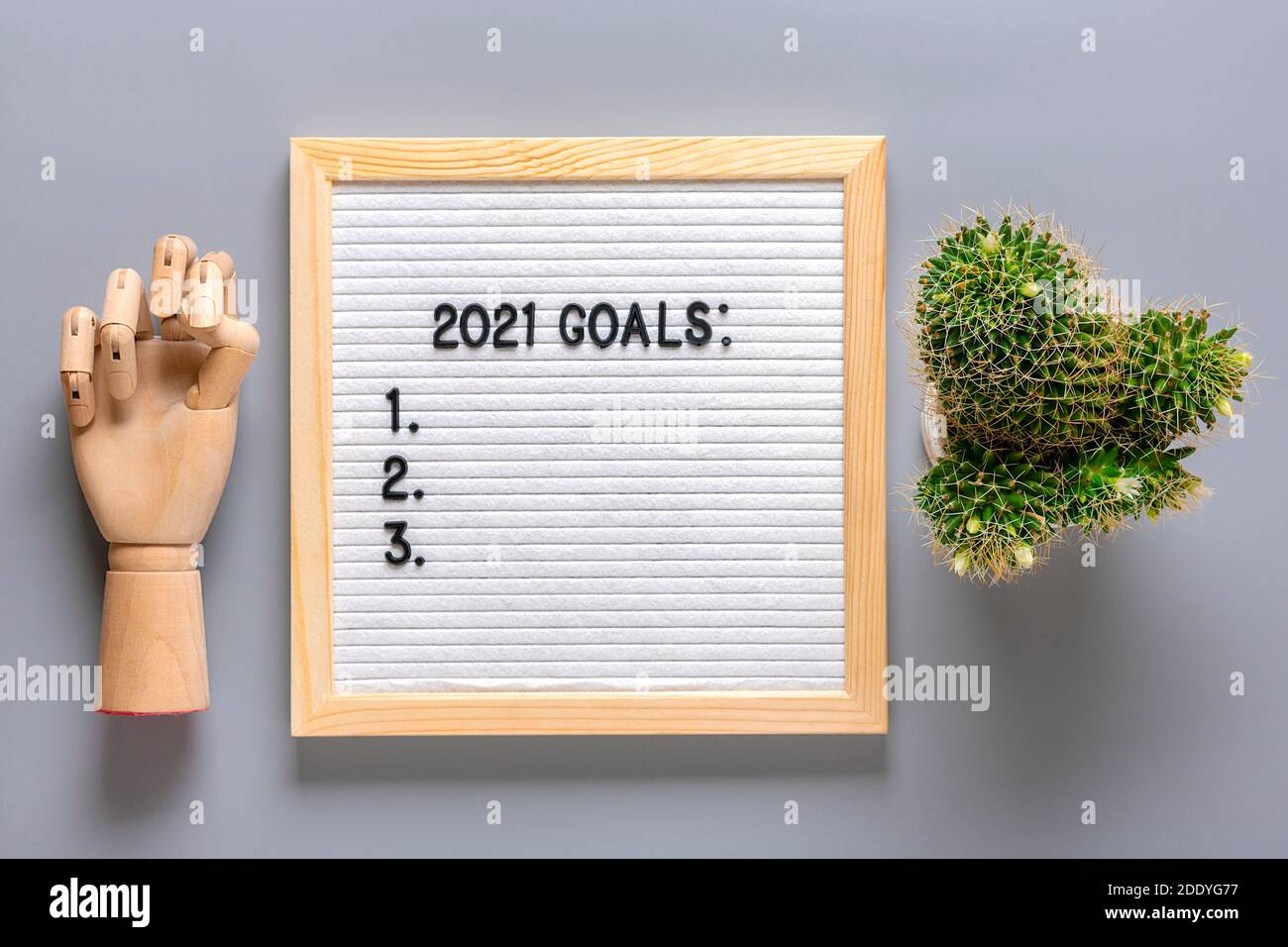 Text - 2021 goals Motivational quote on message felt board, wooden hand, cactus on gray background Planning, self motivation, achievement, success Stock Photo