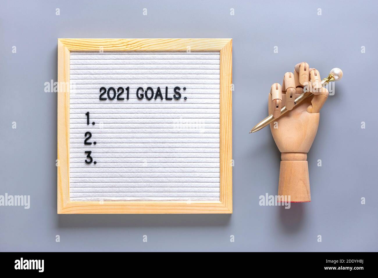 Text - 2021 goals Motivational quote on message felt board, wooden hand, pen on gray background Planning, self motivation, achievement, success, wish Stock Photo