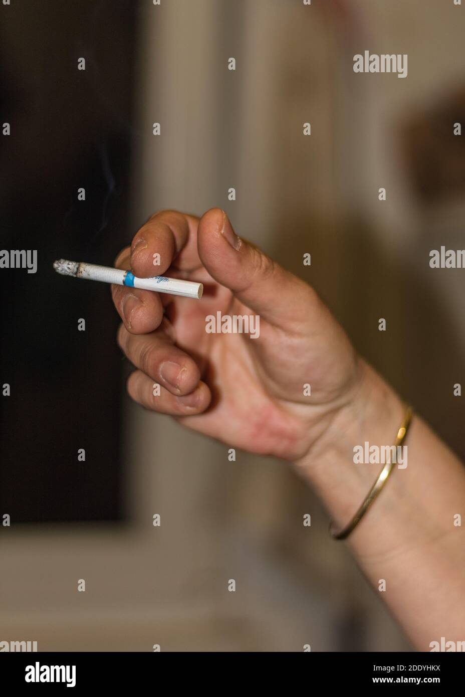 Human hand with a bracelet holding a cigarette Stock Photo - Alamy