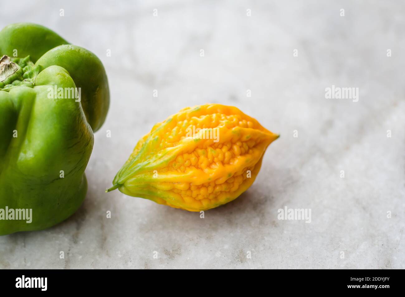 yellow bitter gourd between green capsicum with isolated background