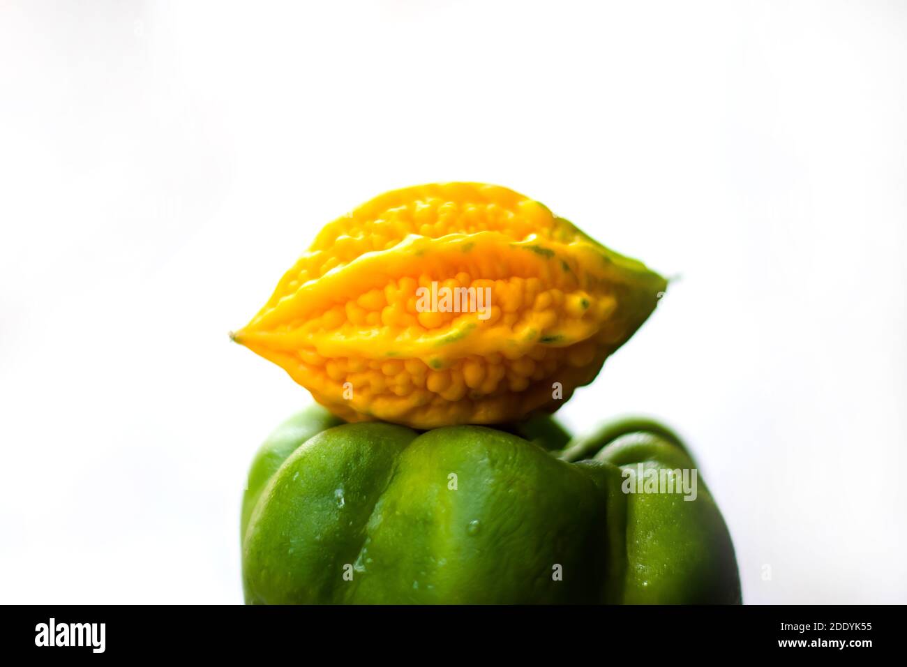 yellow bitter gourd between green capsicum with isolated background