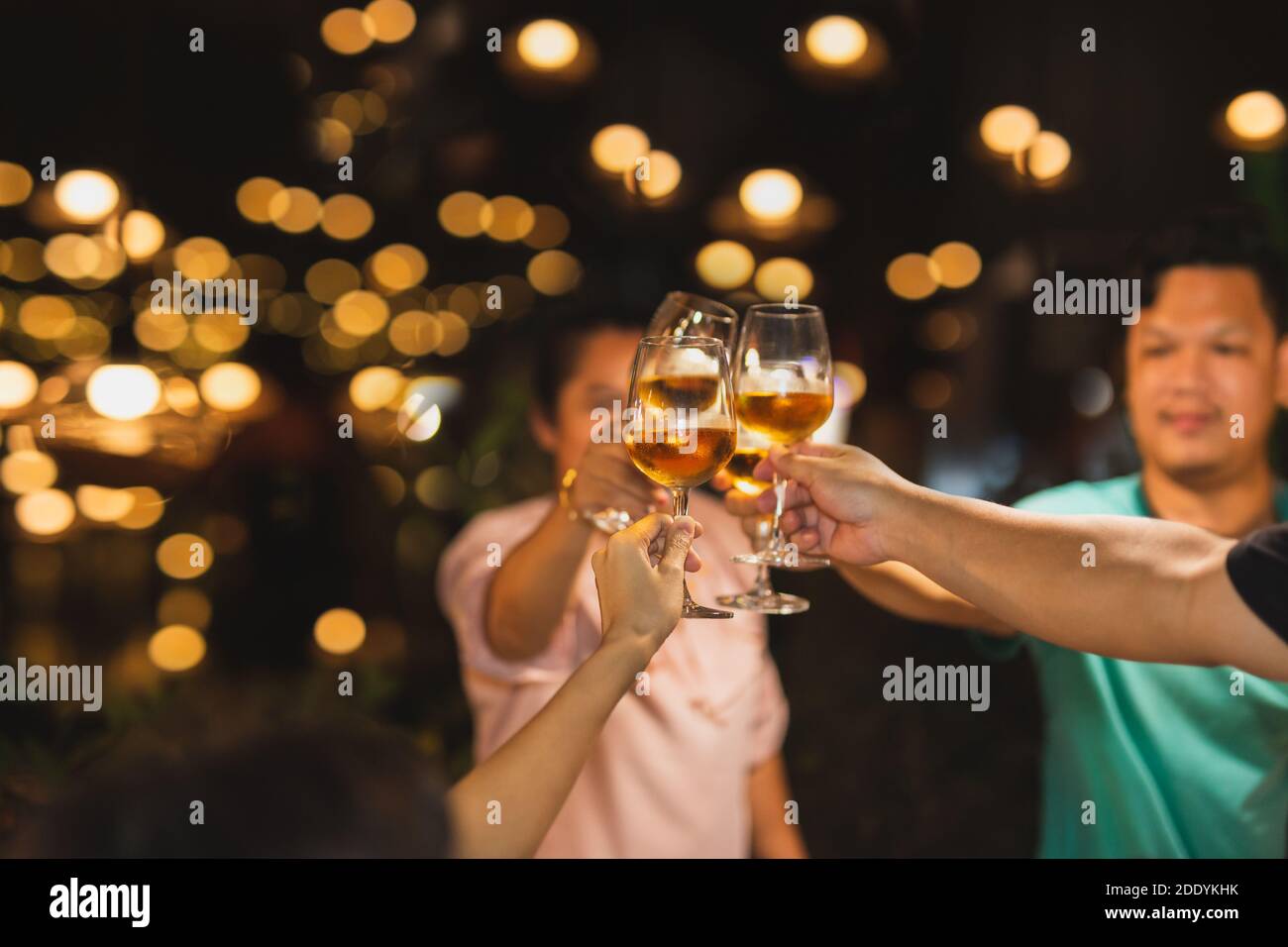 Shot in high iso with low light group of friends toasting with wine for celebration. Stock Photo