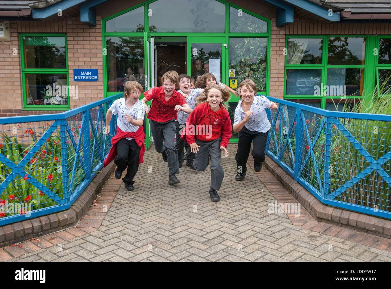 School boys race out of their school at the end of their primary years eager for the summer holidays and Big school. Stock Photo