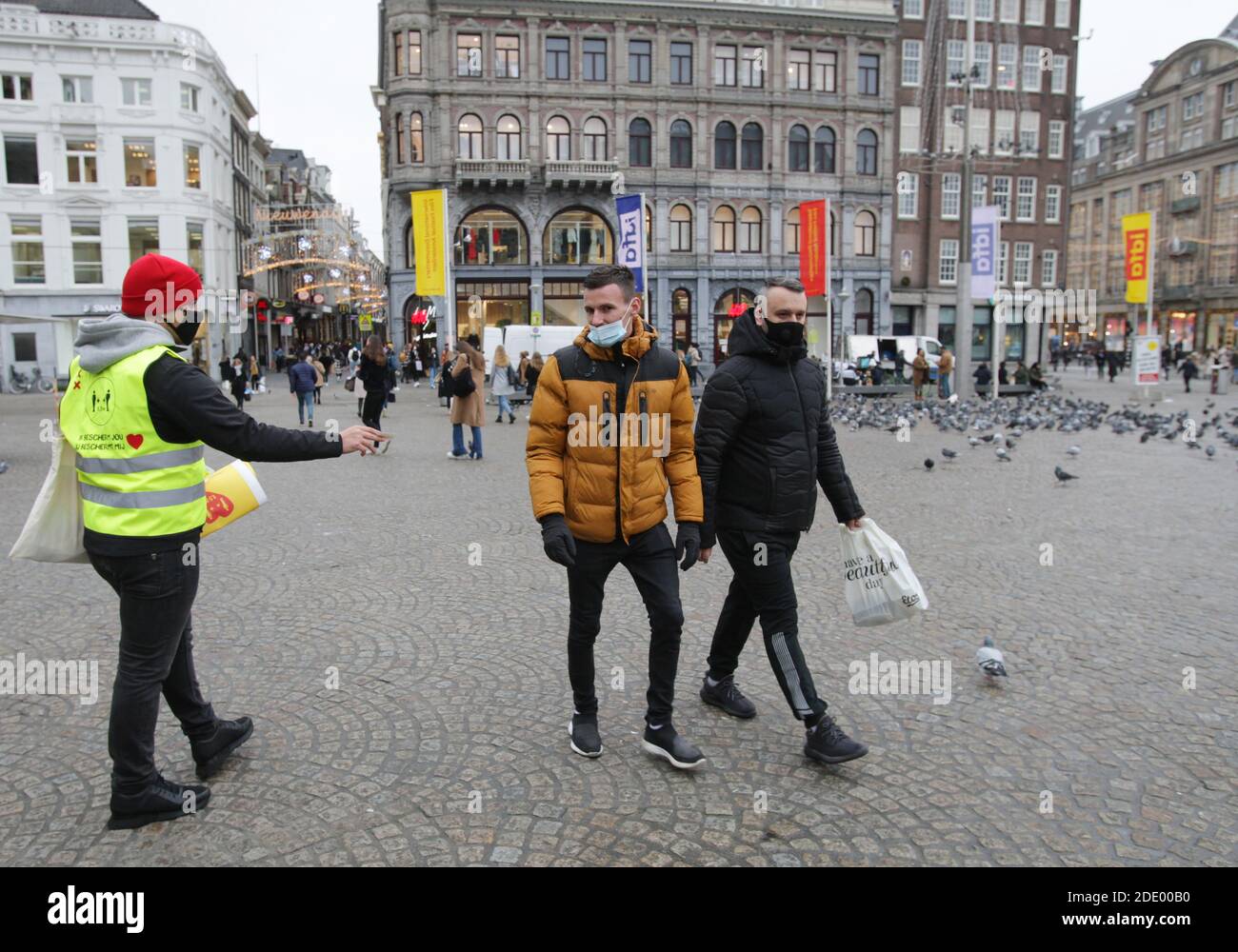 Amsterdam, Netherlands. 27th Nov, 2020. A municipal employee distributes posters for consumers to avoid busy places and keep social distance and wear protective face masks during 'Black Friday' at the Dam square near shopping street Kalverstraat amid the Coronavirus pandemic on November 27, 2020 in downtown Amsterdam, Netherlands. (Photo by Paulo Amorim/Sipa USA) Credit: Sipa USA/Alamy Live News Stock Photo