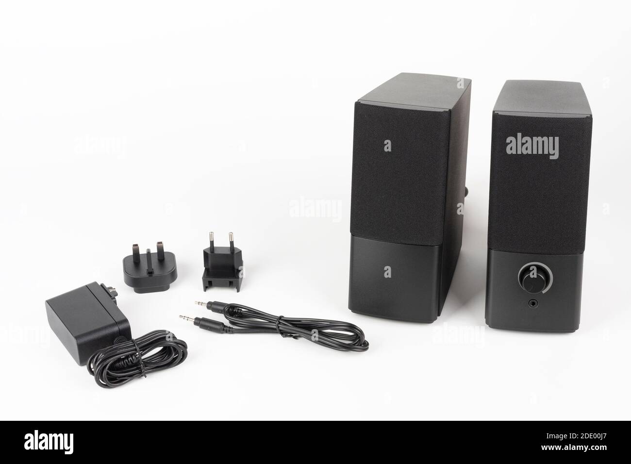 Two computer speakers on white background. AC adapter with European