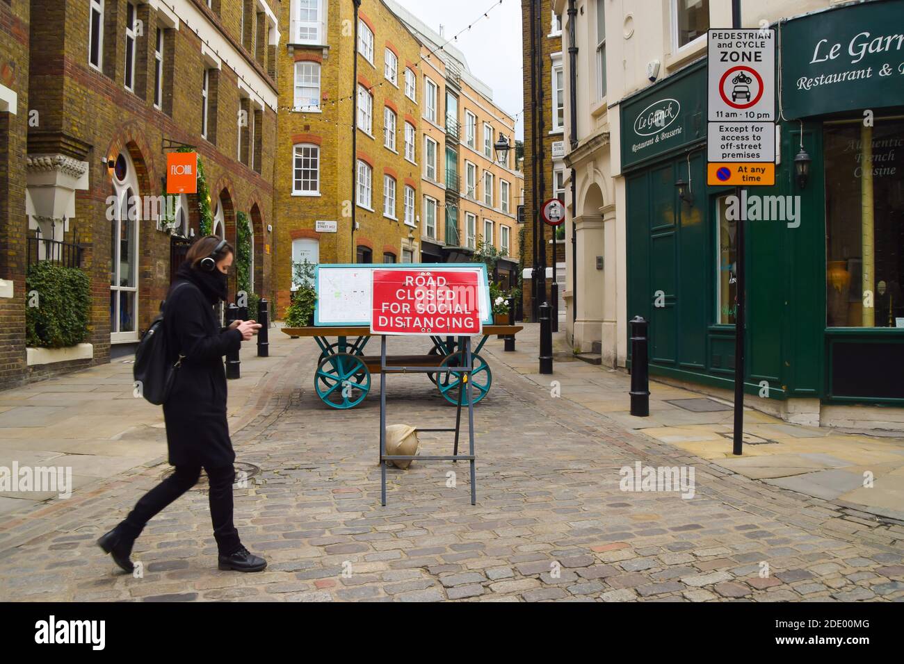 A woman wearing a protective face mask walks past a Road Closed For Social Distancing sign in Covent Garden, London. Stock Photo