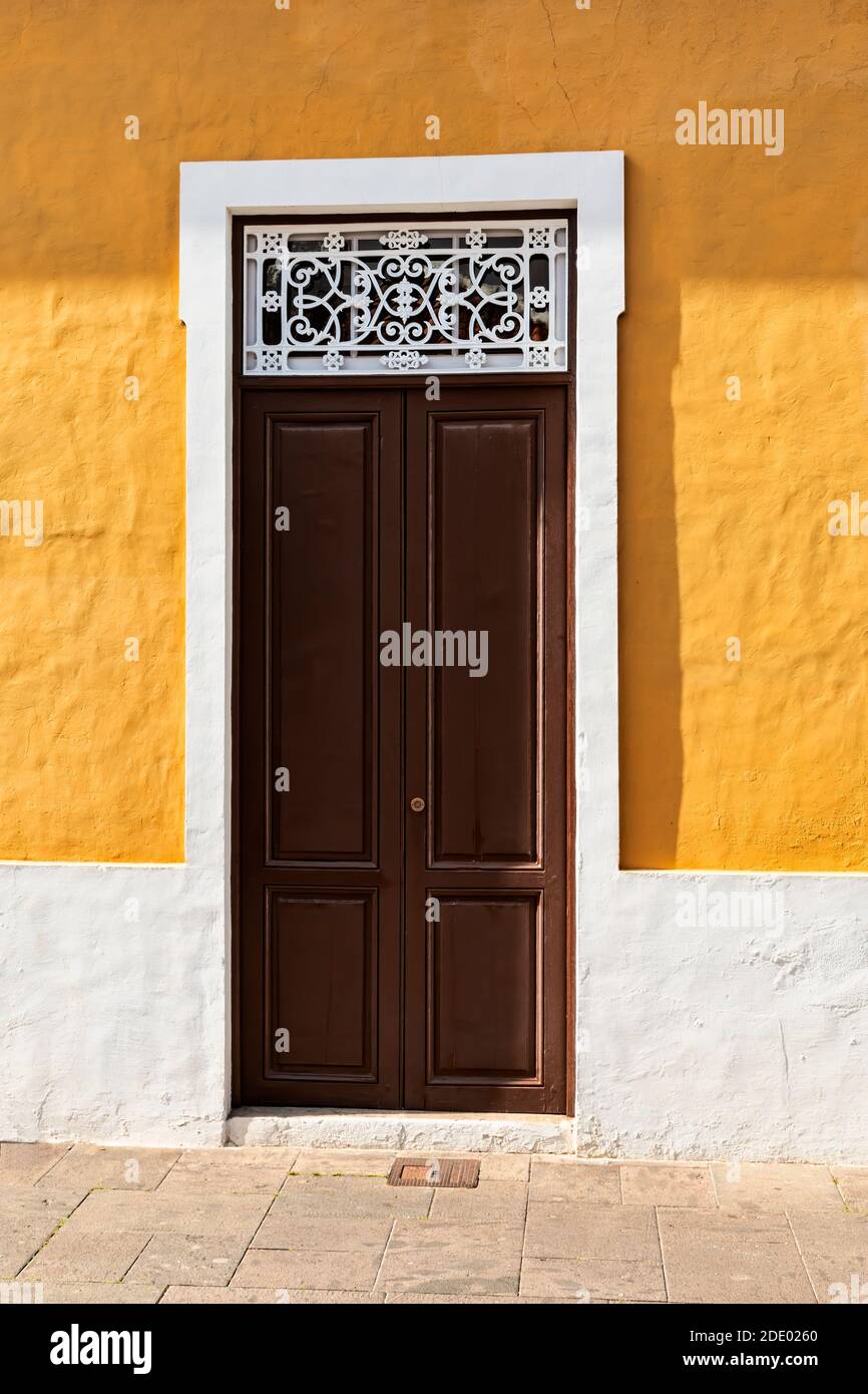 Brown double door in a yellow wall. Shot from Tenerife, Spain Stock Photo