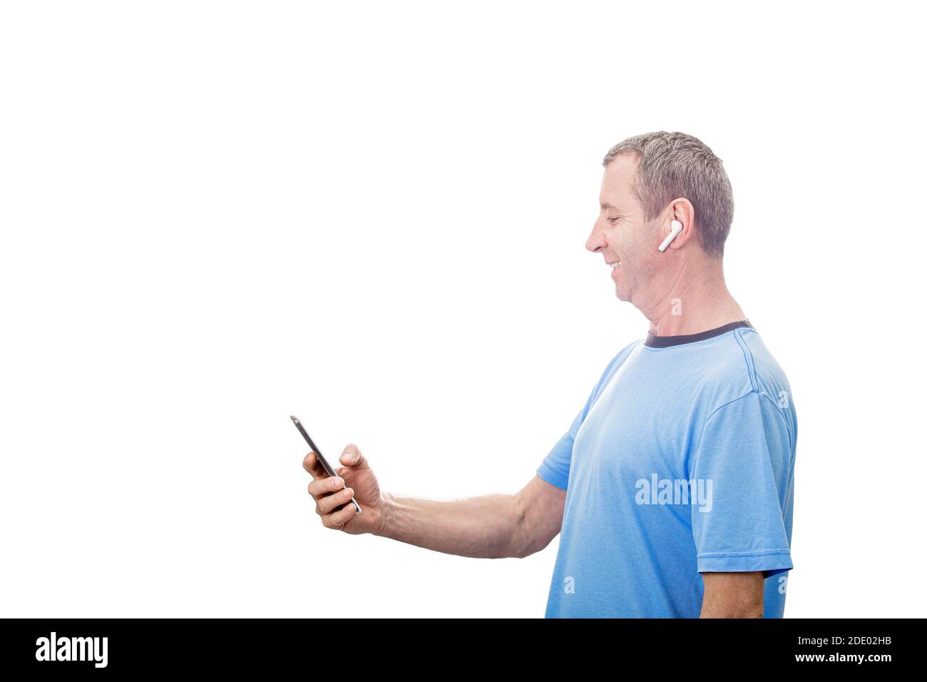 Smiling Middle aged man using  smartphone texting while listening to music over white background . Man listening to music or media on his mobile phone Stock Photo