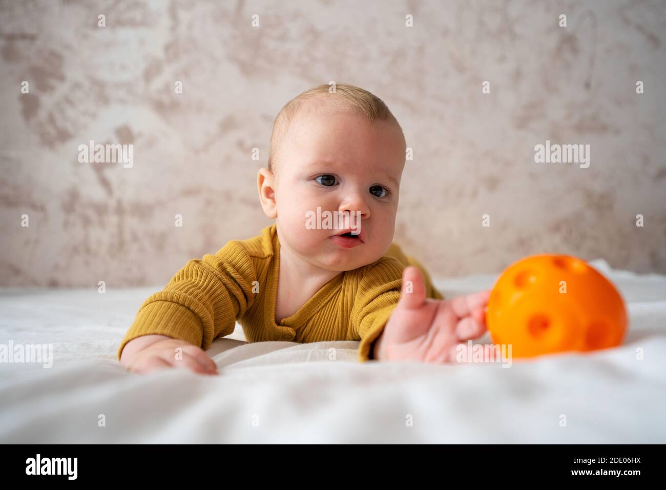 Cute baby playing with ball on bed Stock Photo Alamy