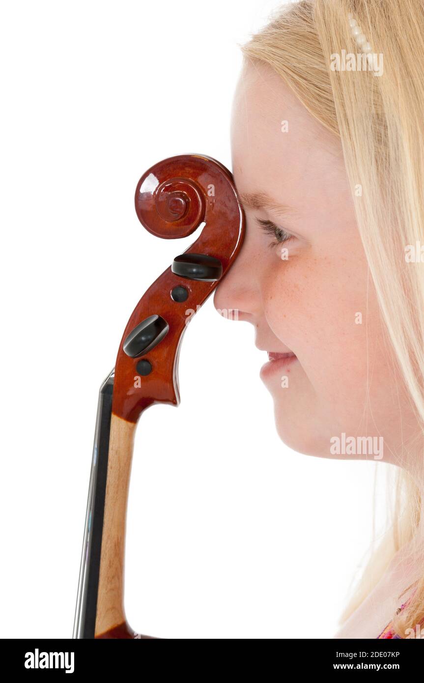 Close up of happy young blonde girl with the head of a violin pressed against the bridge of her nose. Stock Photo