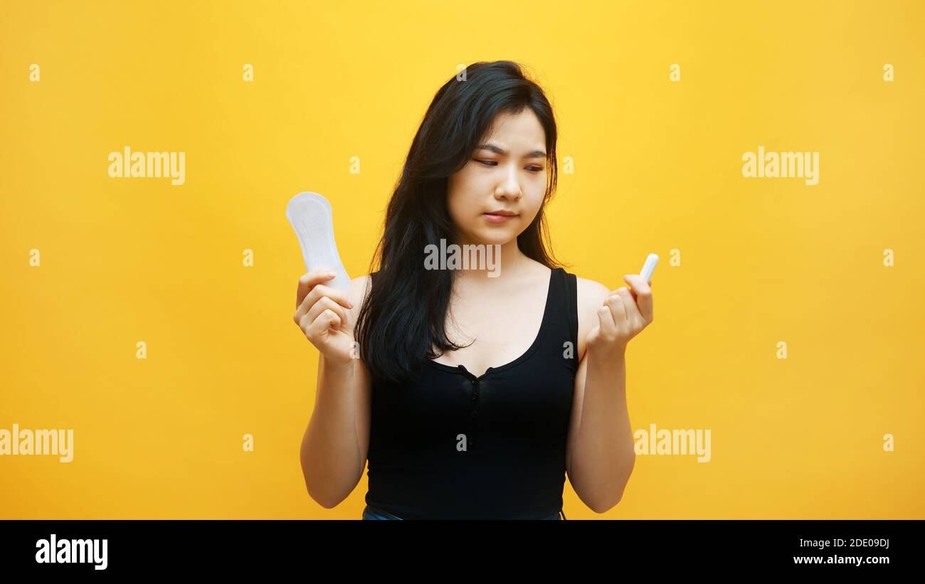 Young frustrated asian woman suffering from PMS. Choice between
