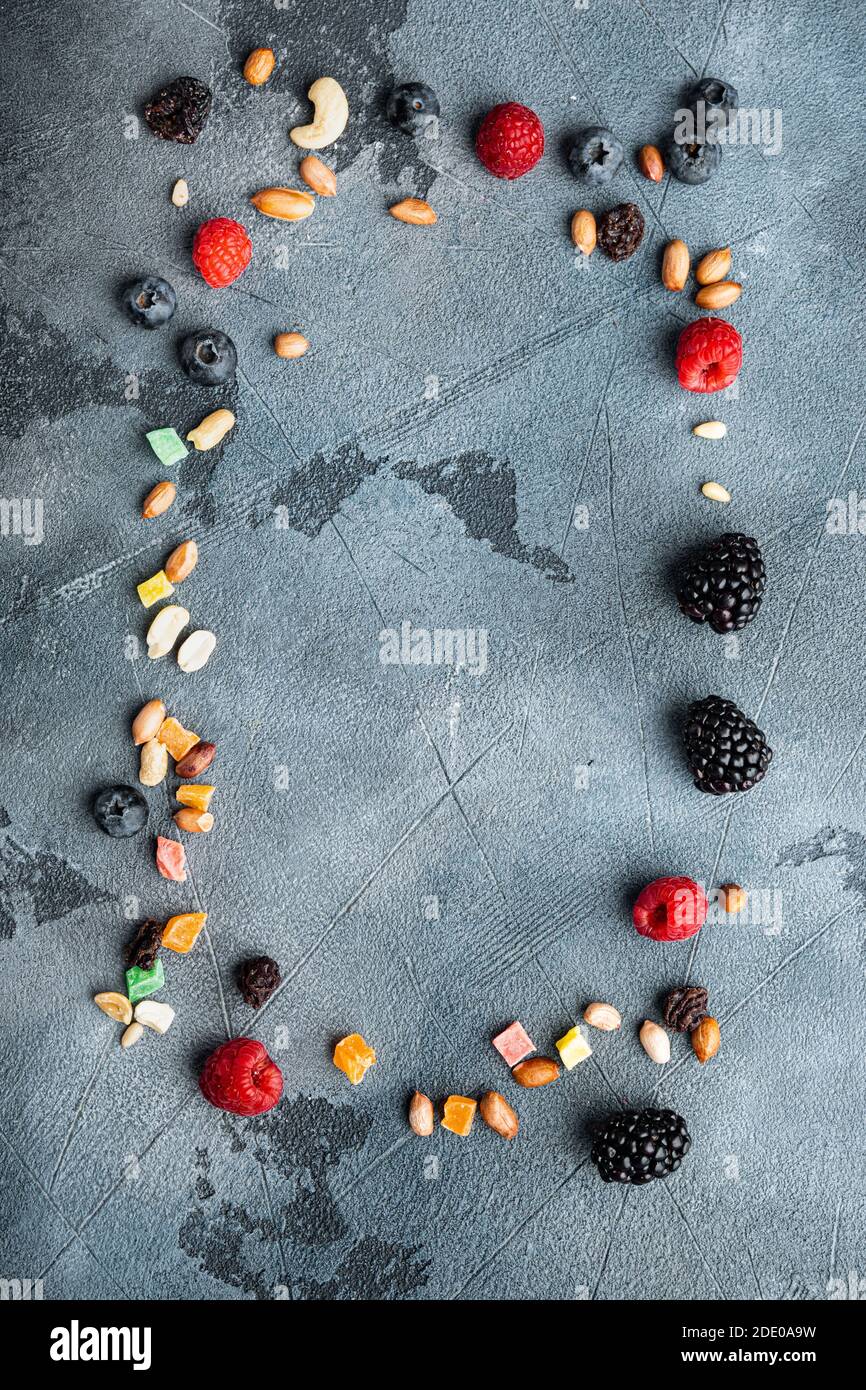 Frame made of mixed dried and raw ripe berry and fruits with nuts, top view with copy space, on grey background Stock Photo