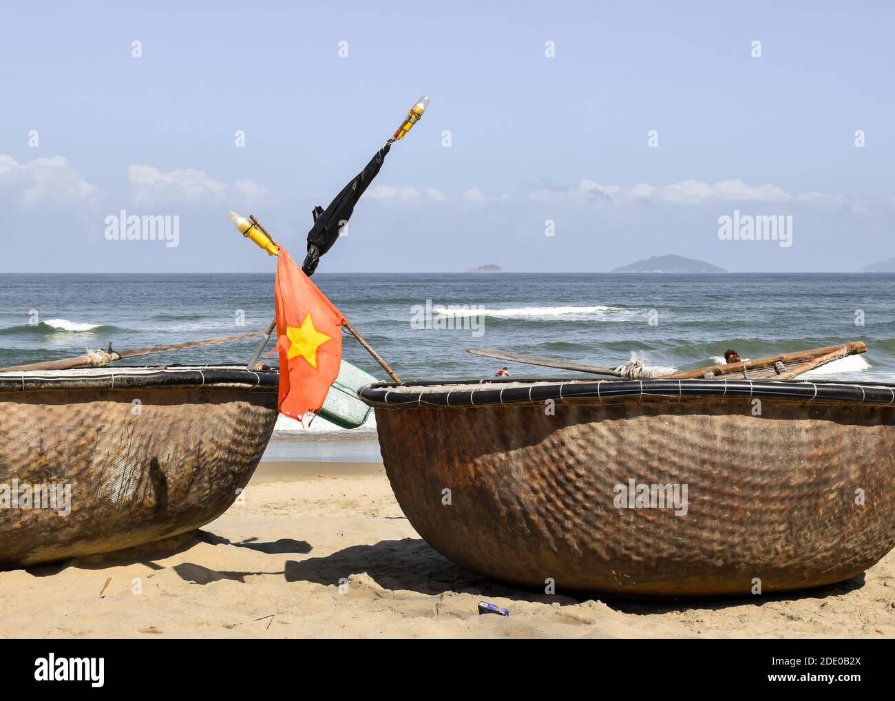 Close-up of basket boats on the sand in front of the sea. There is a Vietnam flag in one of them. An Bang Beach, Hoi An, Vietnam. Stock Photo