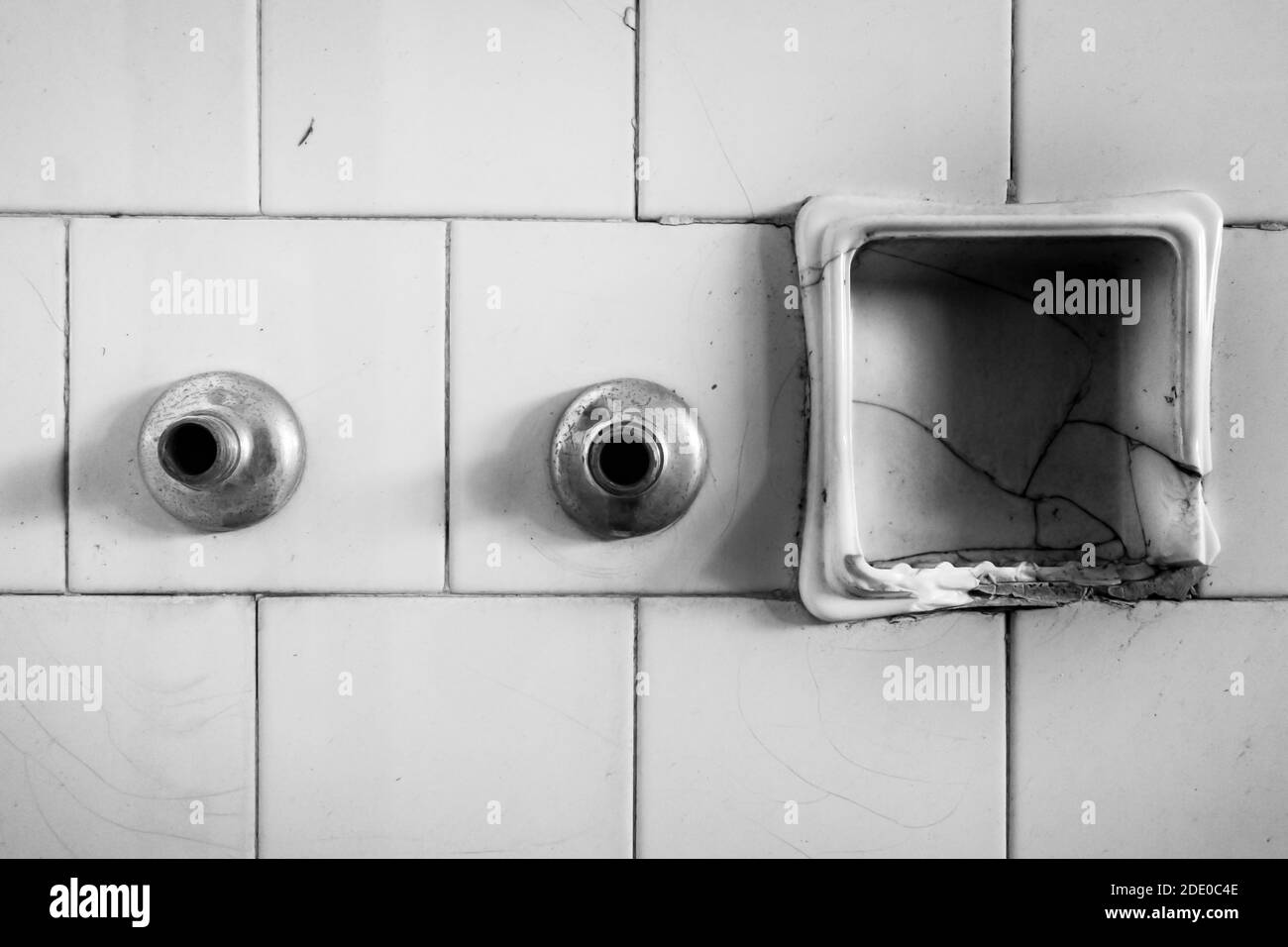 Black and white of bathroom detail. Tiled wall, broken ceramic soap
