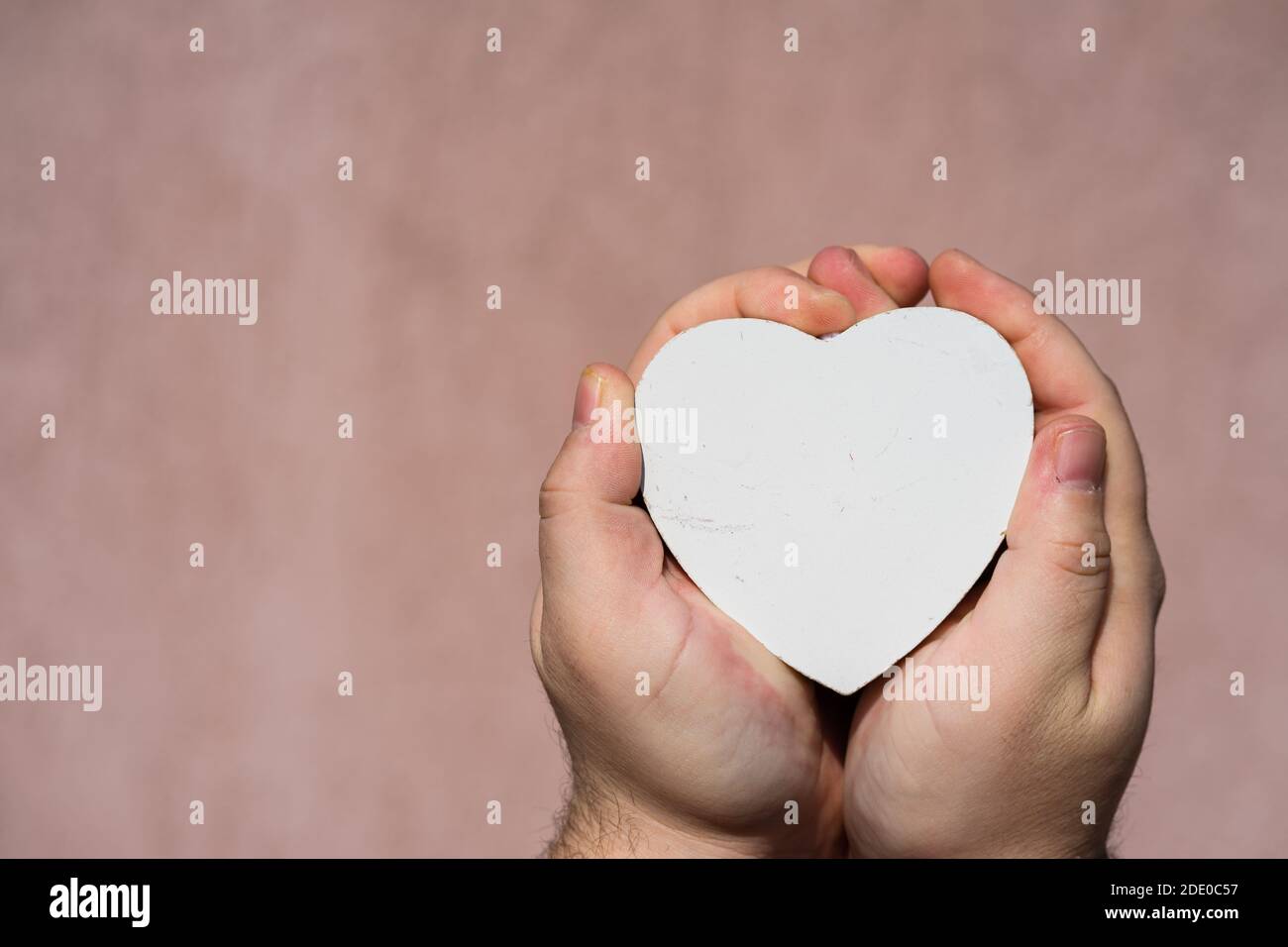 Hands holding a white wooden heart shaped object decoration isolated ...