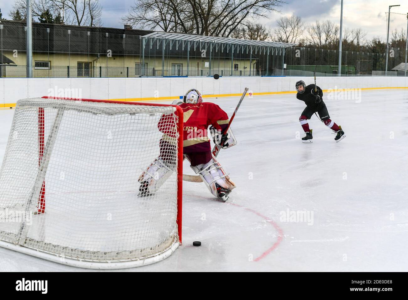 youth hockey player shots on goalie during open air icehockey training