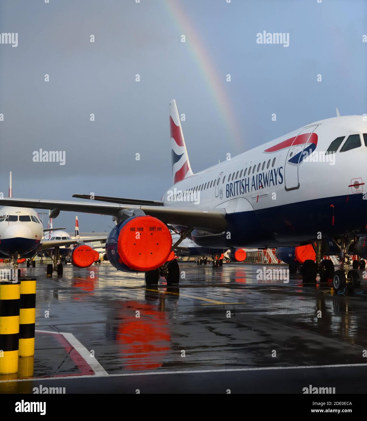 Rain cloud and rainbow over a grounded British Airways plane parked-up at Glasgow International Airport, Scotland, UK Stock Photo
