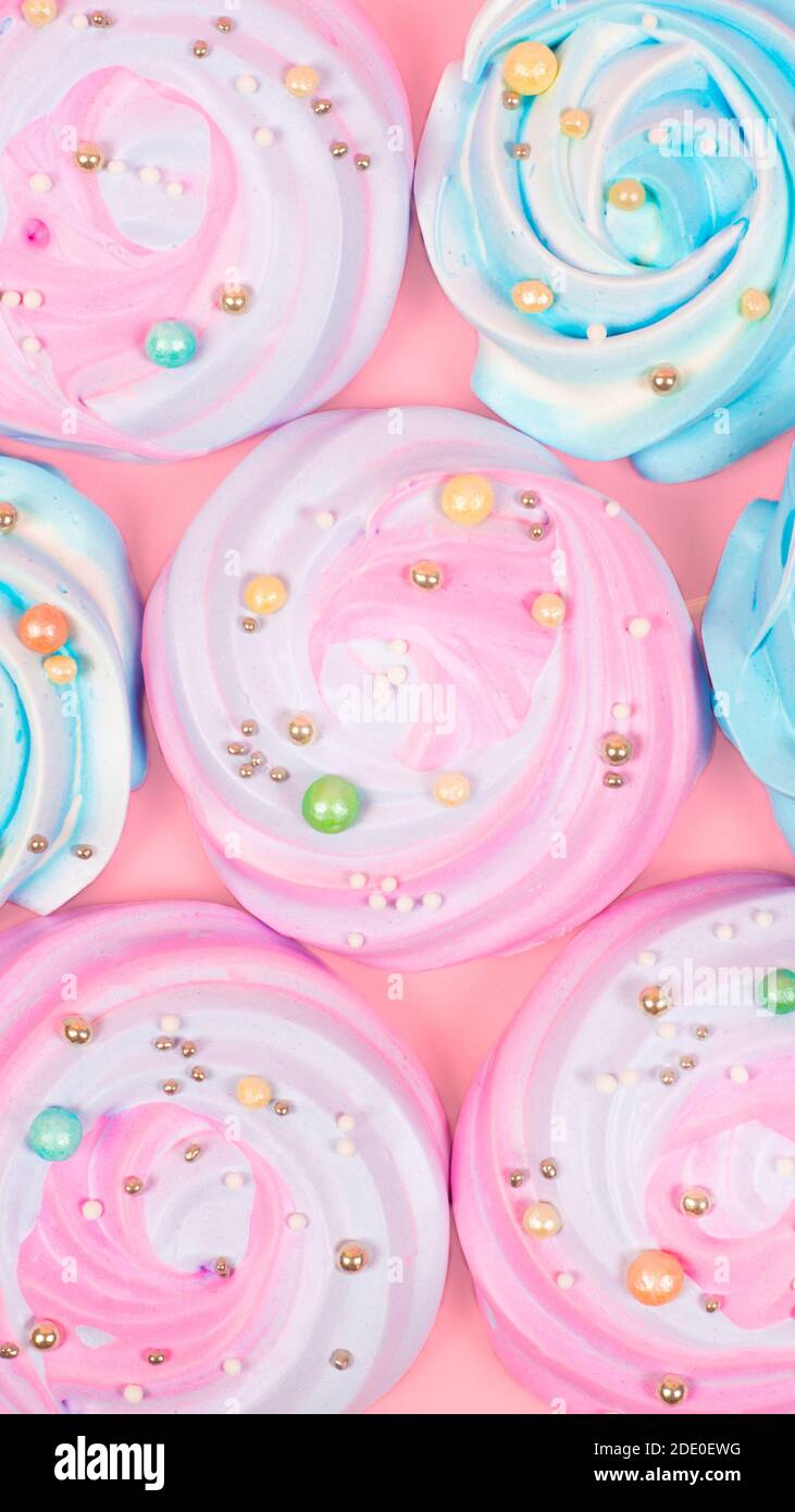 Colorful meringue cake toppers on pastel pink background. Trendy