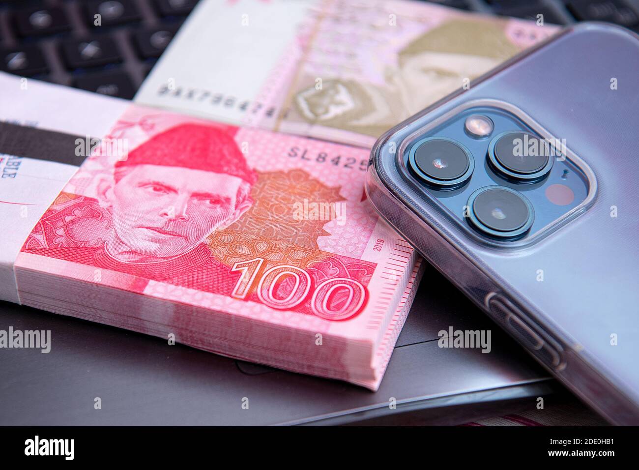 Pakistani Currency 100 rupees Banknote with iphone 12 pro max . Business and Finance concept Stock Photo