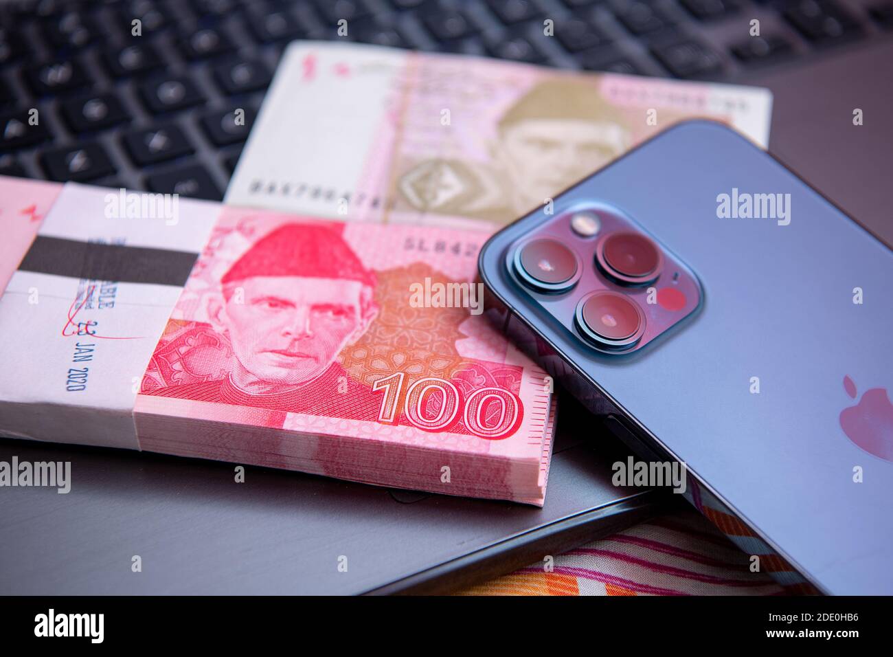 Pakistani Currency 100 rupees Banknote with iphone 12 pro max . Business and Finance concept Stock Photo