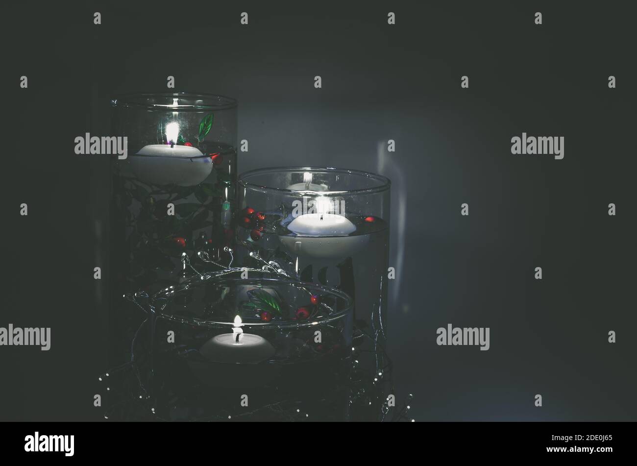 burning candles floating on water in vase full of water and colorful