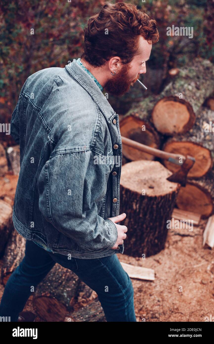 Brutal redhead guy with cigarette gets ready to chop wood Stock Photo