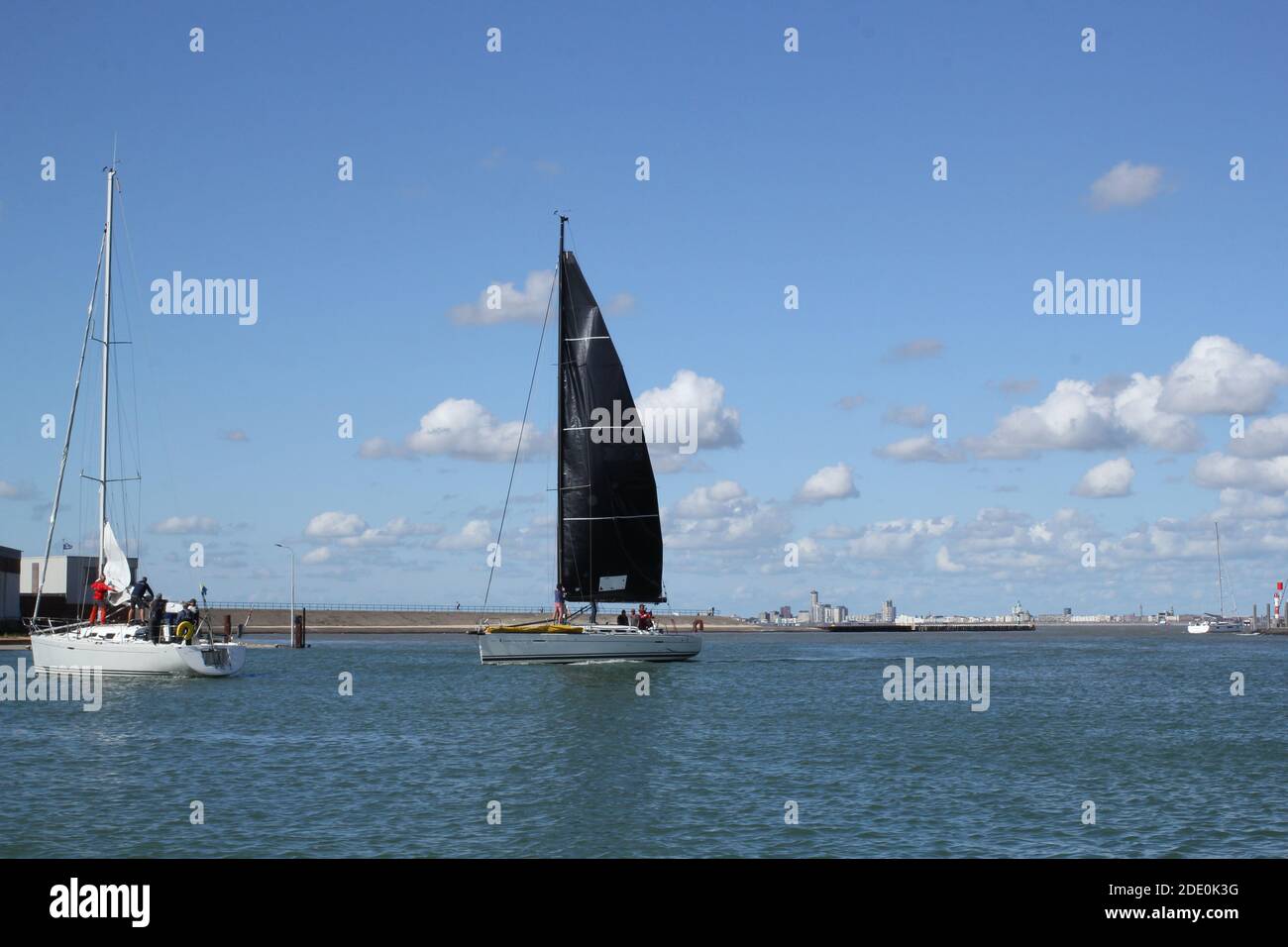 a sailboat with a black sail in arriving in the harbor in Breskens, zeeland, the netherlands after an ocean race in summer in europe Stock Photo