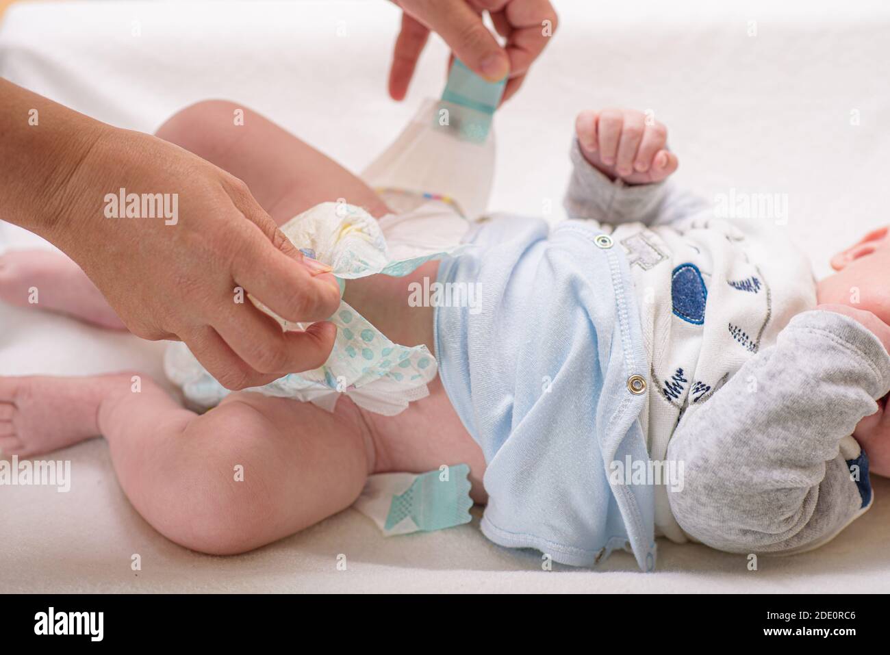 Mother changing diaper of adorable baby with a hygiene set for babies on the background Stock Photo