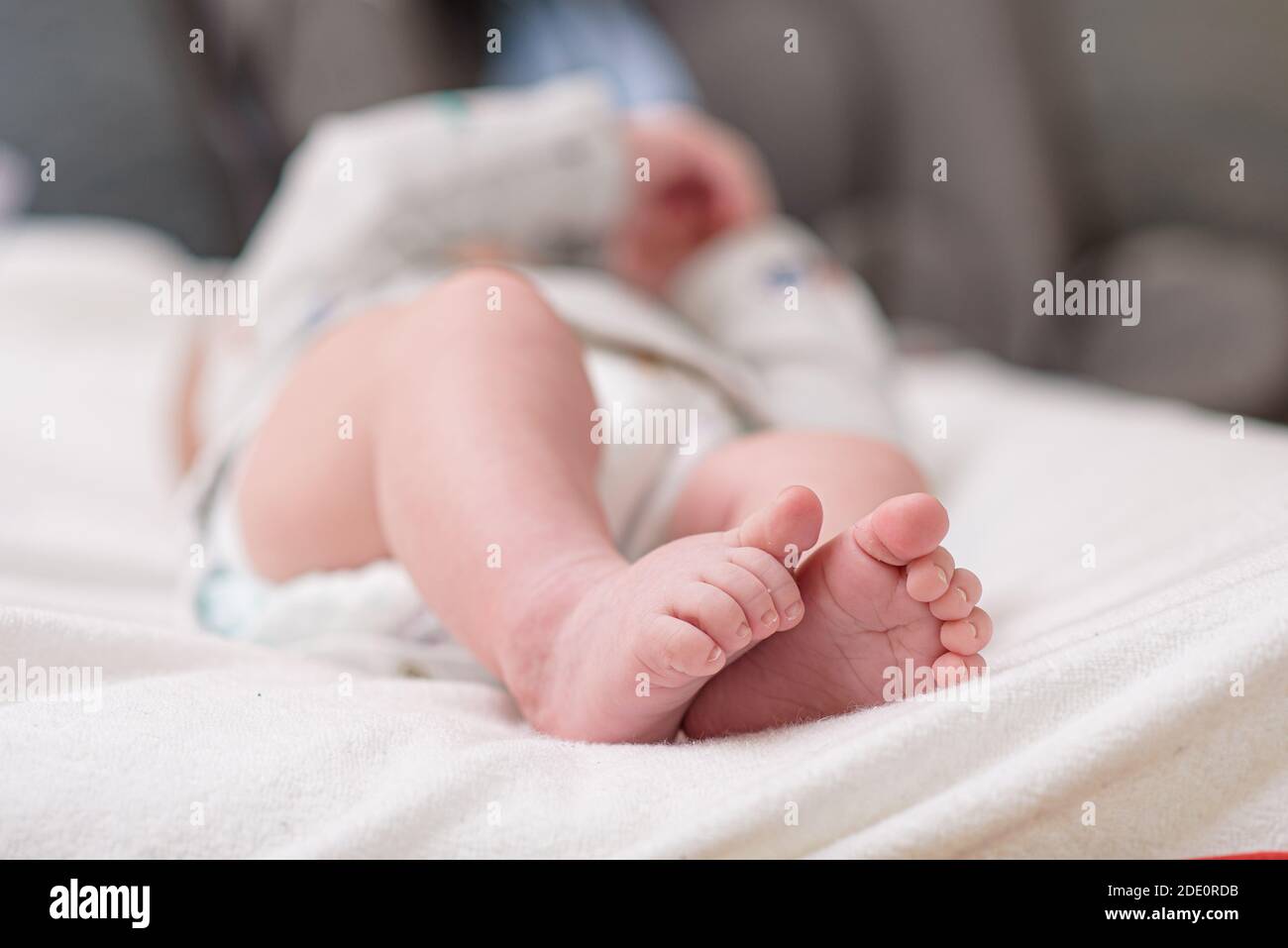 Mother changing diaper of adorable baby with a hygiene set for babies on the background Stock