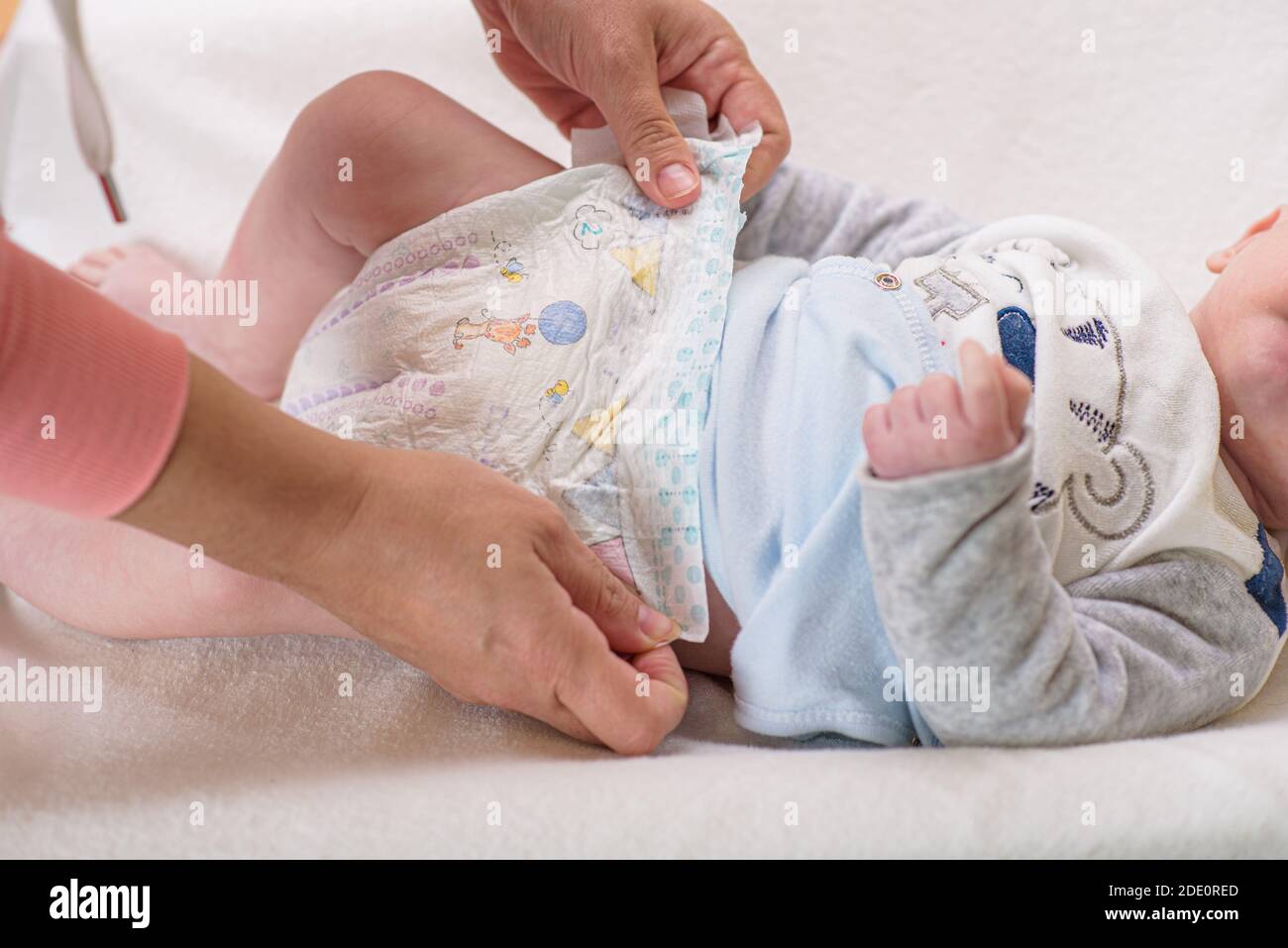 Mother changing diaper of adorable baby with a hygiene set for babies