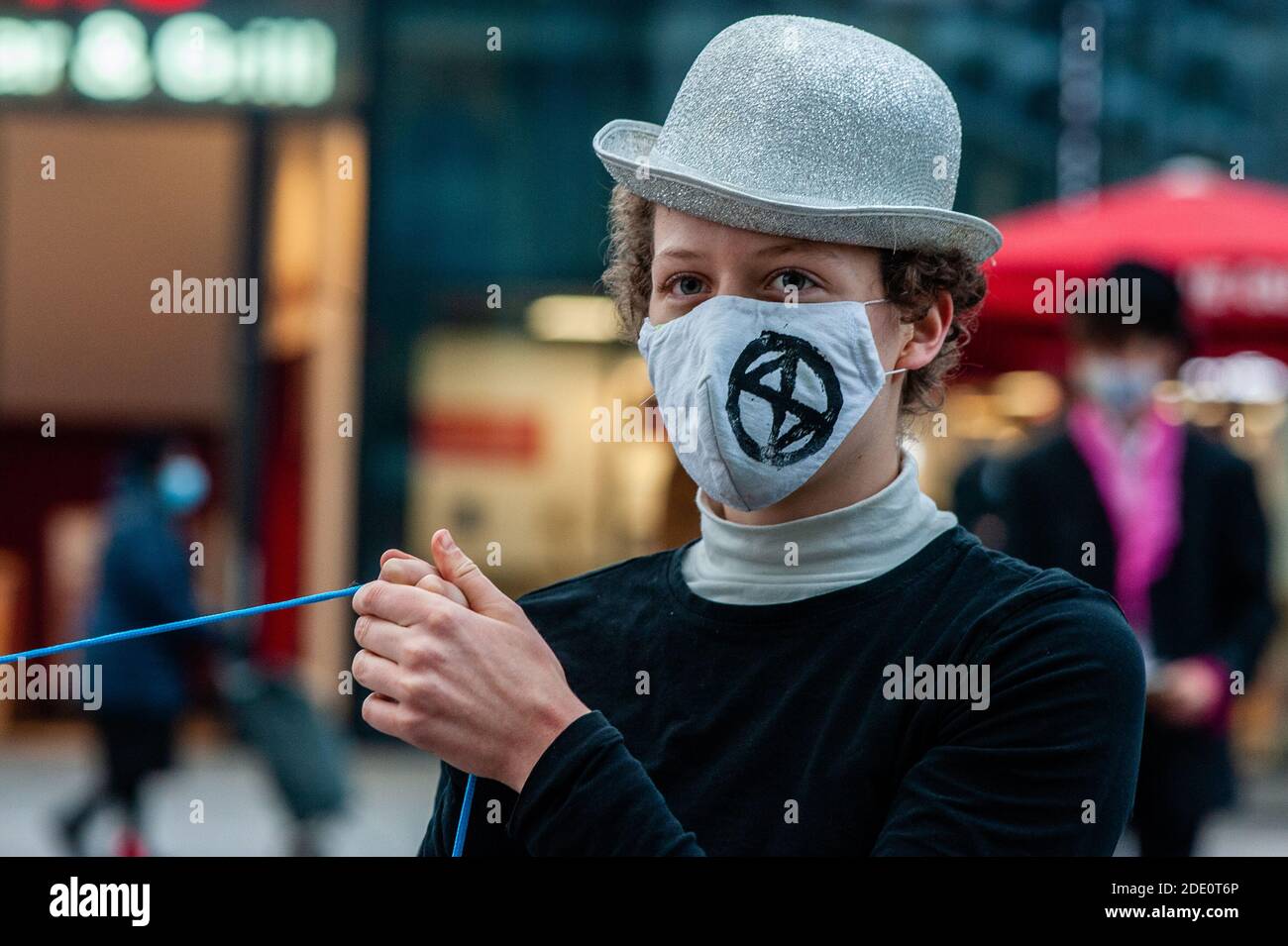 A climate activist is seen wearing a face mask with the XR logo on it during the demonstration.In many cities around The Netherlands, the climate organization Extinction Rebellion has organized several actions against overconsumption during Black Friday, and to put an end to this day. In Utrecht, the climate activists organized a bizarre circus protest with acrobats and capitalism clowns, to show how they see the 'circus' around Black Friday. The action took place in front of the Hoog Catharijne shopping mall which is one of the largest indoor shopping centers in The Netherlands. Stock Photo