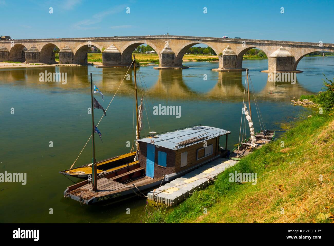 France, Loiret (45), Gien, traditional flat-bottomed boat called in french 'toue cabanée', Loire river and back the old bridge alsol called Anne-de-Be Stock Photo