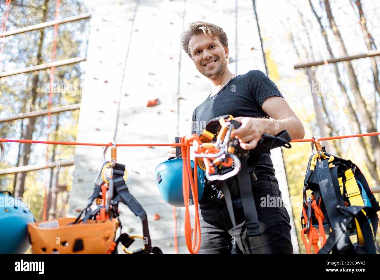 Handsome man wearing safety equipment for climbing at amusement park