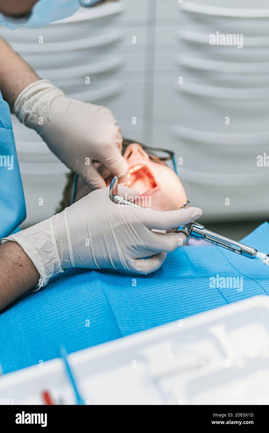 Stock photo of unrecognized dental clinic worker using needle to put