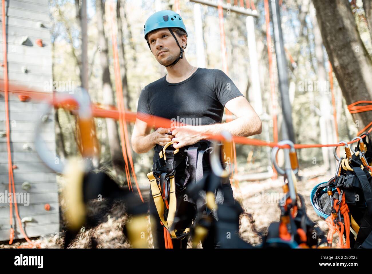 Handsome man wearing safety equipment for climbing at amusement park