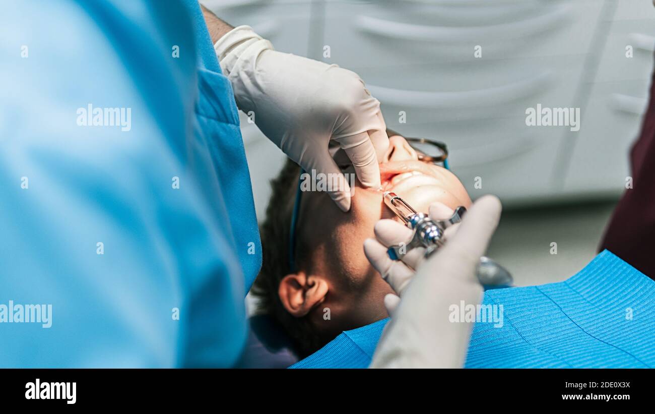 Stock photo of unrecognized dental clinic worker using needle to put