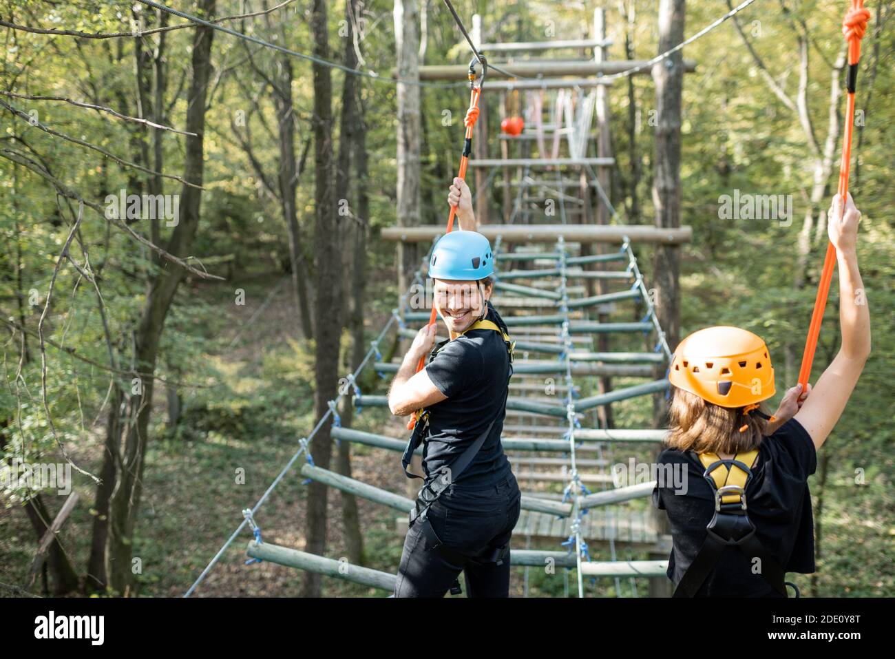 Climbing With Ropes Well-equipped man and woman having an active recreation, climbing ropes ...