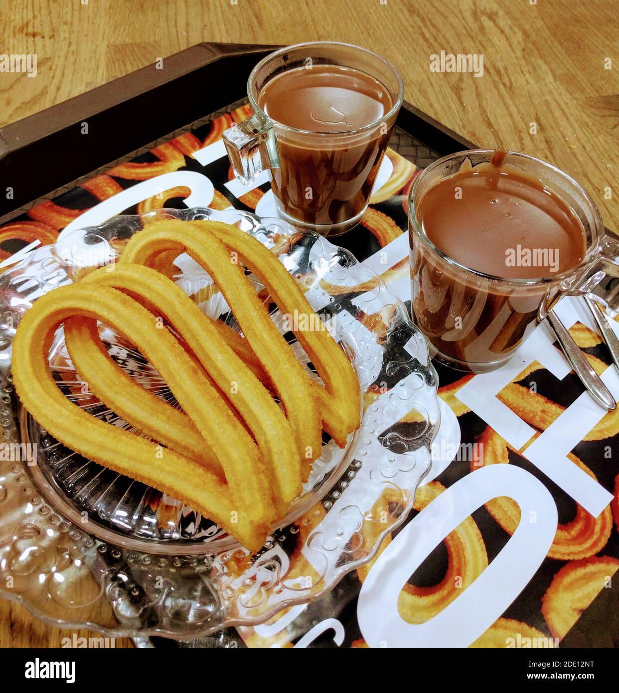 Traditional spanish churros with hot chocolate on a wooden table. Traditional spanish sweet baked goods. Stock Photo